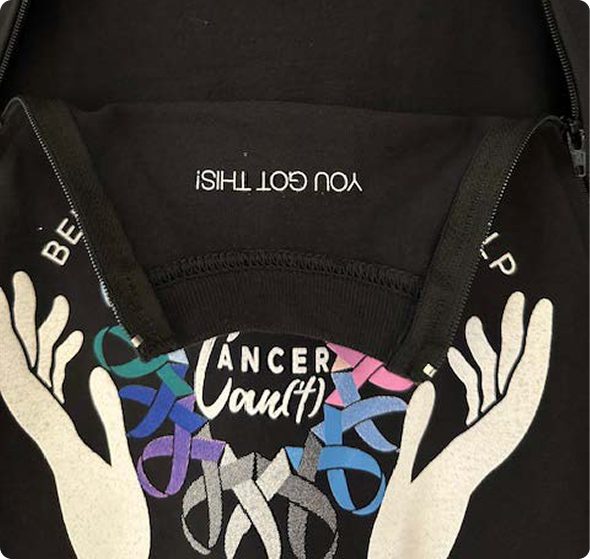 Hands holding a ribbon with the words 'Cancer Counts' on a black background.