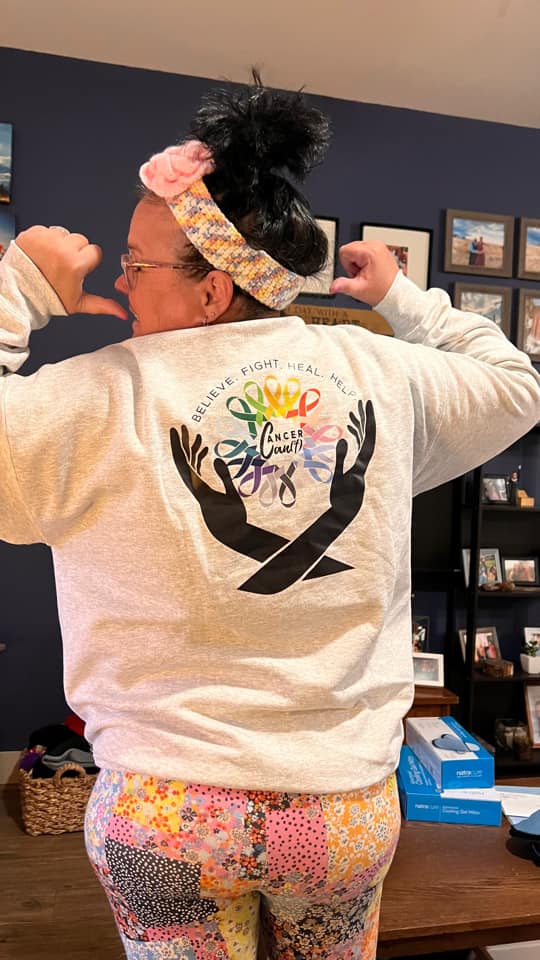 Person wearing a white sweatshirt with a colorful, artistic design on the back.