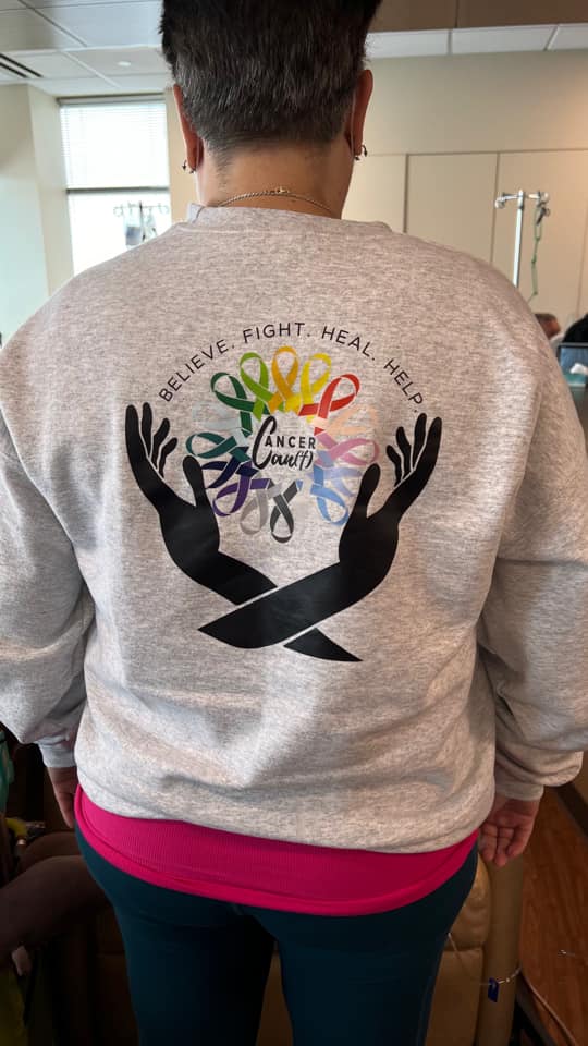 Gray sweatshirt with colorful heart and black silhouetted hands design.